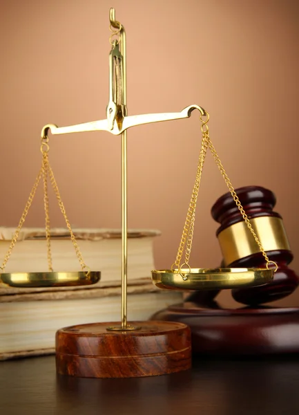 Golden scales of justice, gavel and books on brown background — Stock Photo, Image