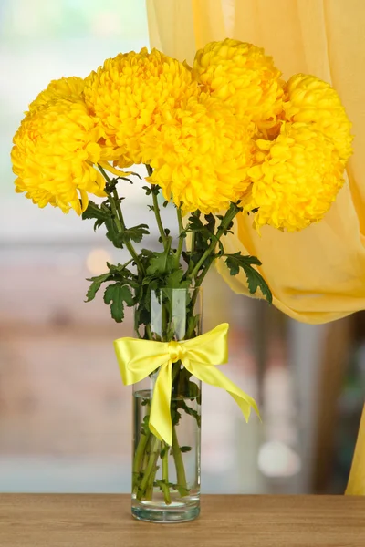 Helder gele chrysanten in glazen vaas, op houten tafel — Stockfoto