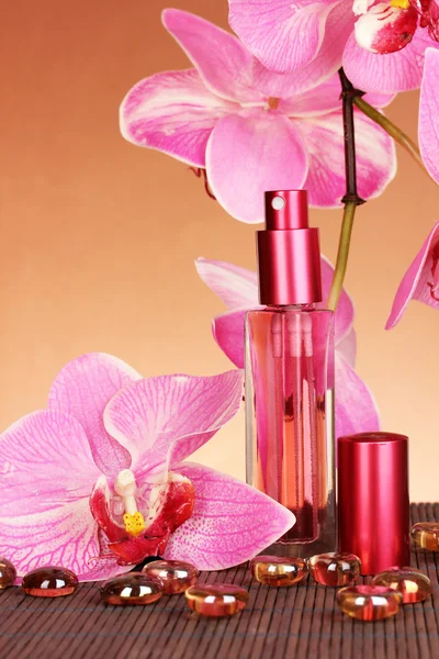 Perfume de mujer en hermosa botella con orquídeas sobre fondo marrón — Foto de Stock