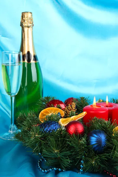 Όμορφα Χριστούγεννα στεφάνι στη σύνθεση με σαμπάνια σε φόντο μπλε ύφασμα — Φωτογραφία Αρχείου
