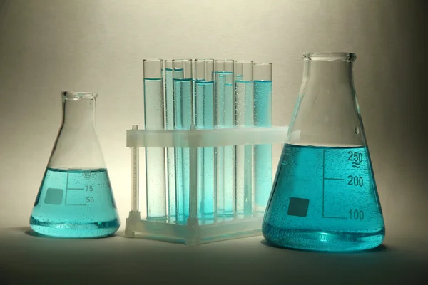 Тестовые трубки с голубой жидкостью на сером фоне — стоковое фото