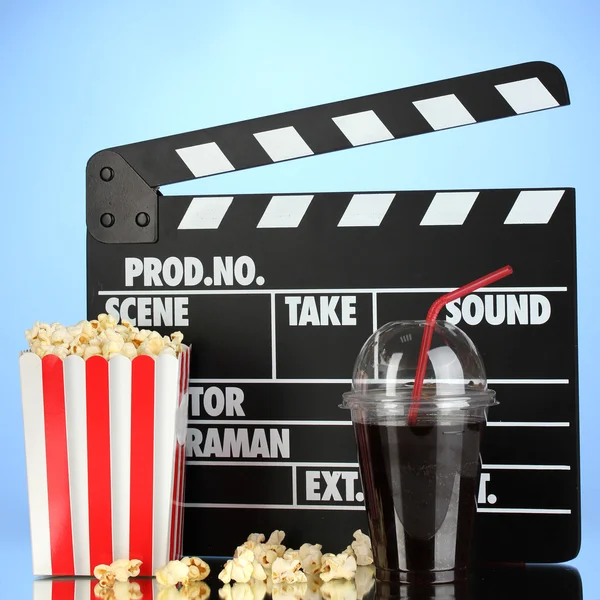 Bordo del film, cola e popcorn su sfondo blu — Foto Stock