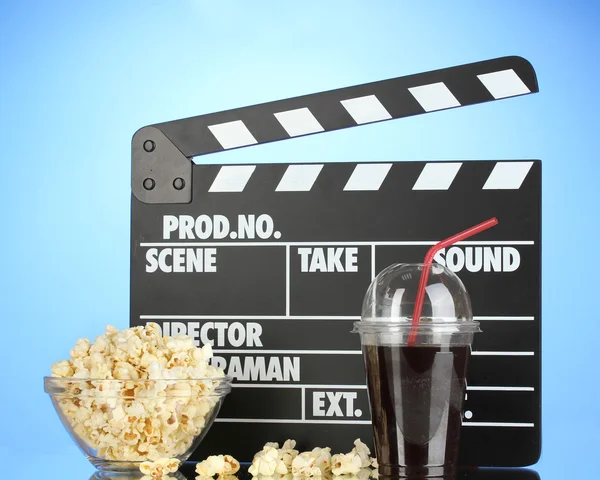 Filmklappbrett, Cola und Popcorn auf blauem Hintergrund — Stockfoto
