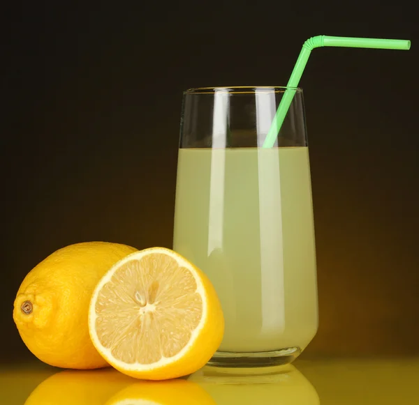 Delicioso zumo de limón en vaso y limones al lado sobre fondo naranja oscuro — Foto de Stock