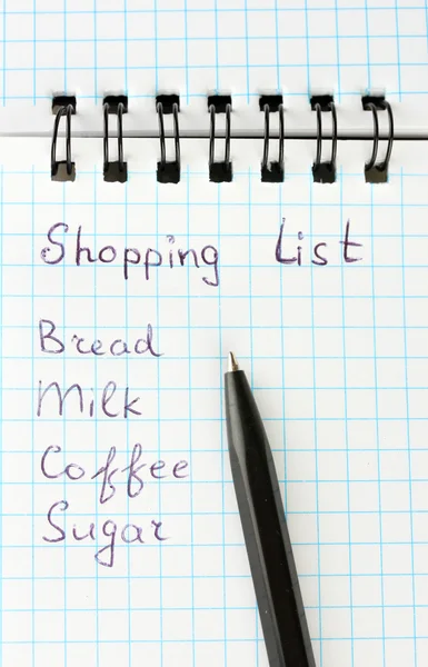 Lista de compras en un cuaderno sobre fondo blanco de cerca — Foto de Stock