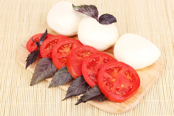 Gustosa mozzarella con pomodori sul tagliere sul tappetino — Foto Stock