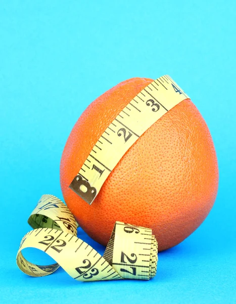 Orange with measuring tape on blue background — Stock Photo, Image