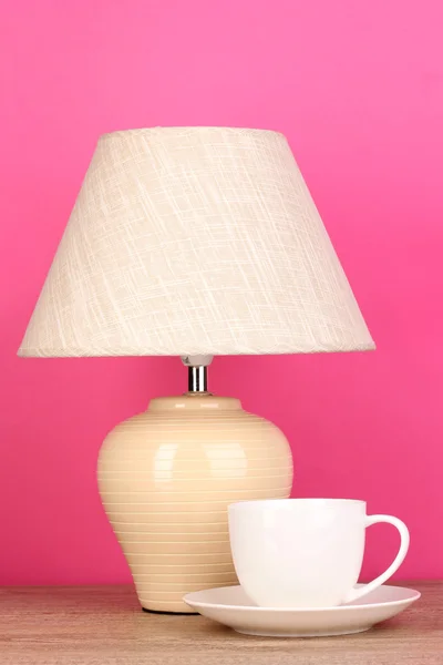 Lampada da tavolo e tazza su sfondo rosa — Foto Stock