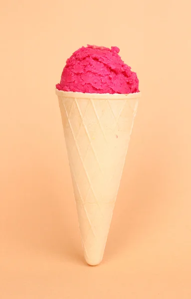 Cuillère de la crème glacée aux fraises dans le cône de gaufre sur fond de corail — Photo