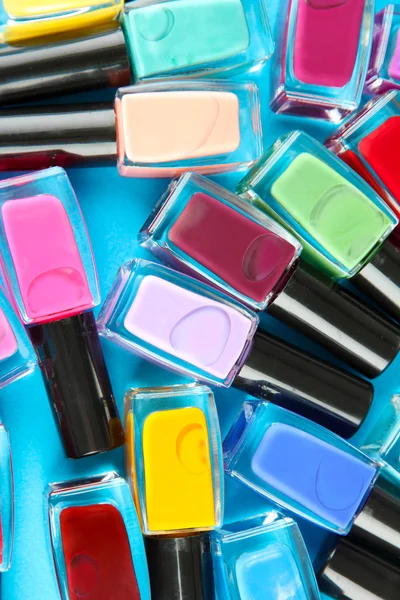 Group of bright nail polishes, on blue background — Stock Photo, Image