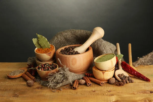 Mortero, cuencos y cucharas con especias, sobre la mesa sobre fondo gris —  Fotos de Stock