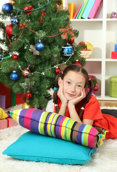 Kleines Mädchen träumt in der Nähe des Weihnachtsbaums — Stockfoto