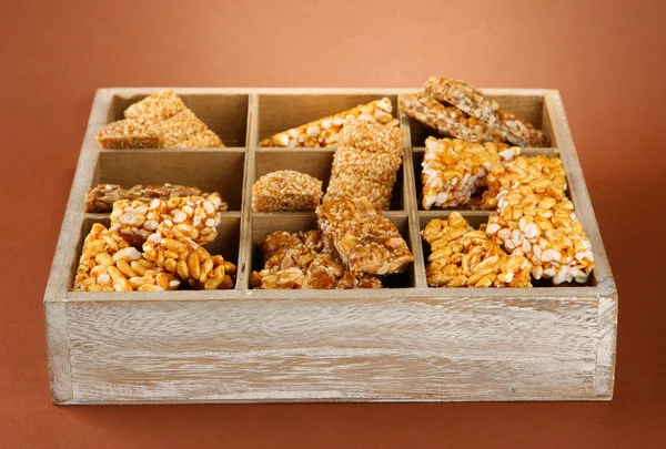 Leckere Süßigkeiten (Kozinaki) in Holzkiste auf braunem Hintergrund — Stockfoto