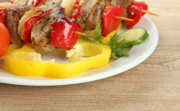 Délicieuse viande et légumes grillés sur brochette sur assiette, sur table en bois — Photo