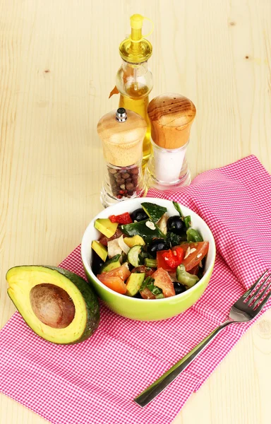 Sabrosa ensalada de aguacate en un tazón rodeado de especias en la mesa de madera de cerca —  Fotos de Stock