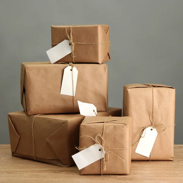 Cajas de paquetes con papel kraft, sobre mesa de madera sobre fondo gris — Foto de Stock