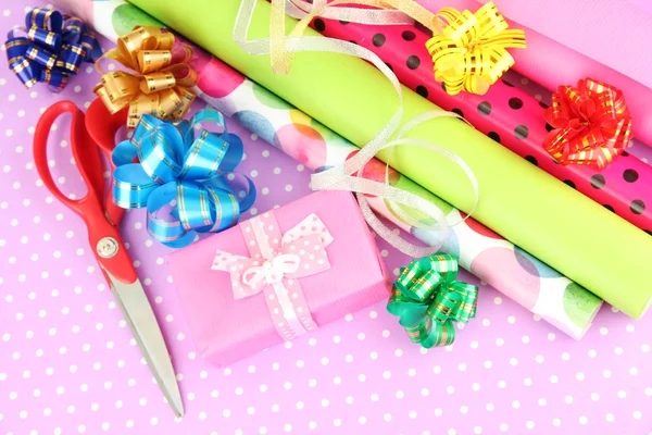 Rollos de papel de regalo de Navidad con cintas, lazos en el fondo de color — Foto de Stock