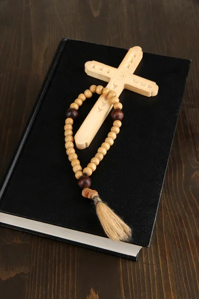 Bible, rosary and cross on wooden table close-up — Stock Photo, Image