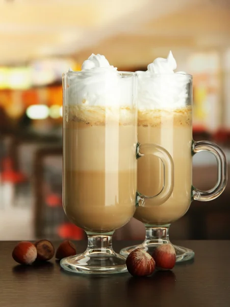 Fragrant coffee latte in glasses cups with nuts, on table in cafe — Stock Photo, Image