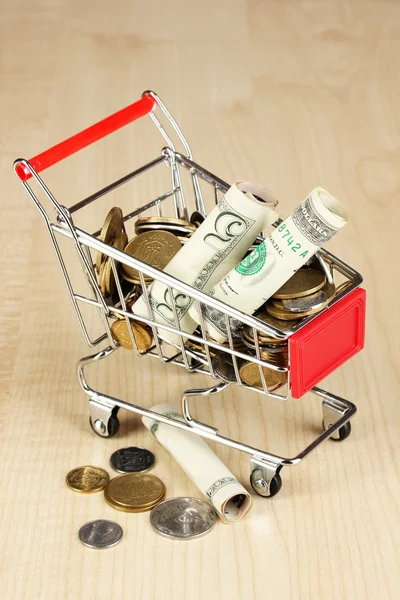 Geld in winkelwagen op houten tafel close-up — Stockfoto