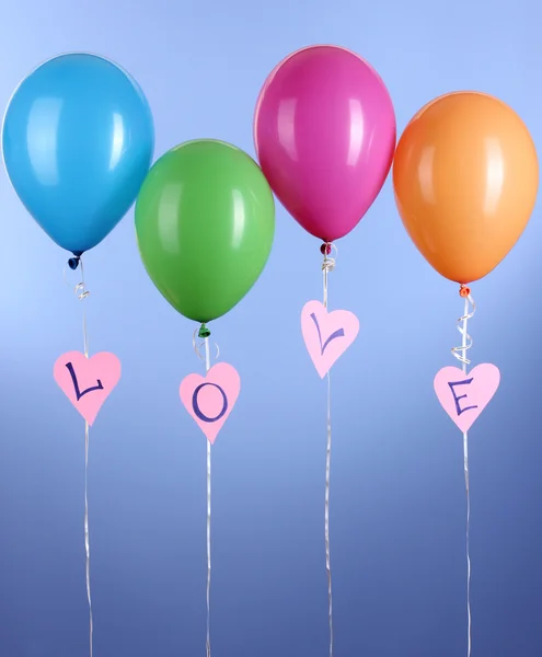 Bunte Luftballons halten Wort Liebe auf blauem Hintergrund — Stockfoto