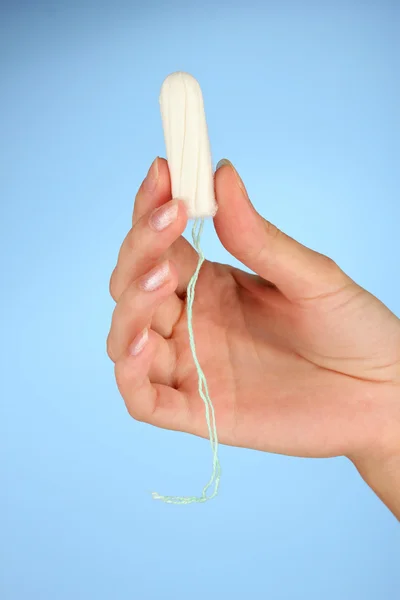 Woman's hand holding a clean cotton tampon on blue background close-up — Stock Photo, Image