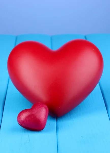 Corazones rojos decorativos sobre mesa de madera azul sobre fondo azul —  Fotos de Stock