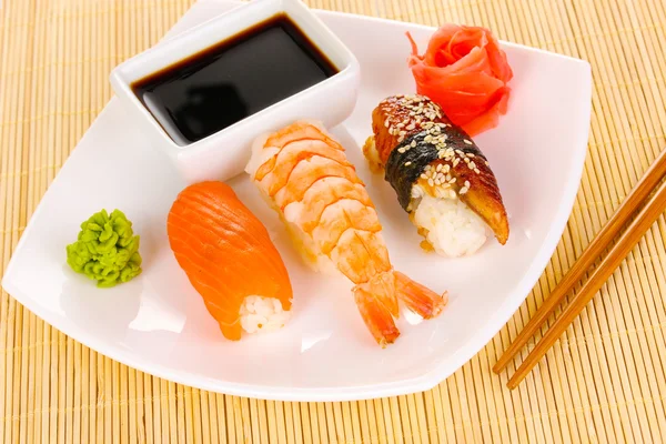 Heerlijke sushi geserveerd op plaat op bamboe mat — Stockfoto