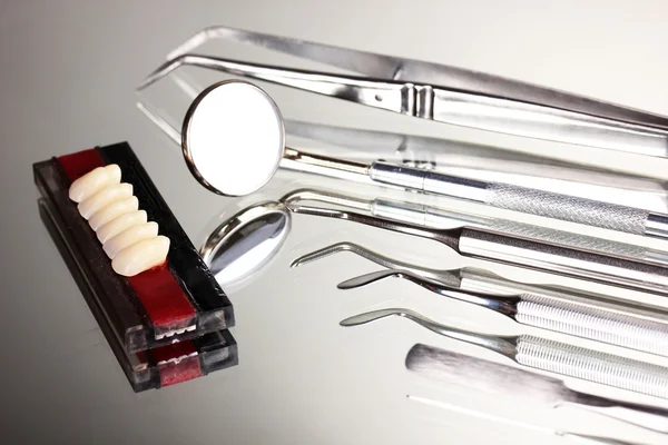 Juego de herramientas dentales con dentadura postiza sobre fondo gris —  Fotos de Stock