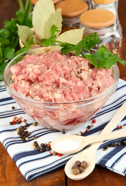 Schüssel mit rohem Hackfleisch mit Gewürzen auf Holztisch — Stockfoto