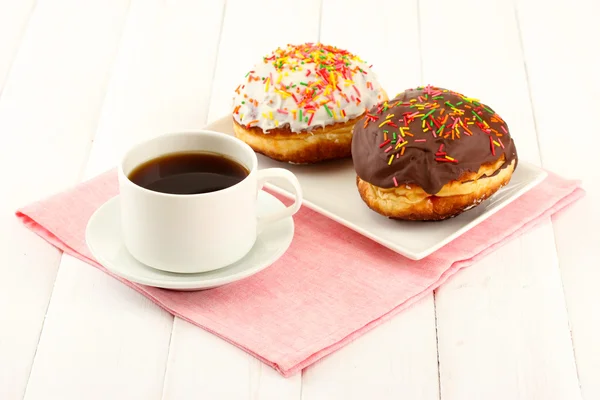 Tasty donuts on color plate on light wooden background — Stock Photo, Image