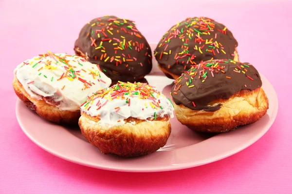 Leckere Donuts auf Farbteller auf Farbhintergrund — Stockfoto