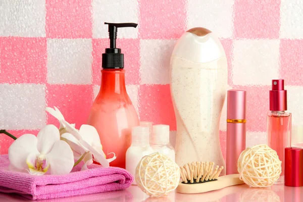 Accesorios de baño en el estante en el baño sobre fondo de pared de baldosas rosa —  Fotos de Stock