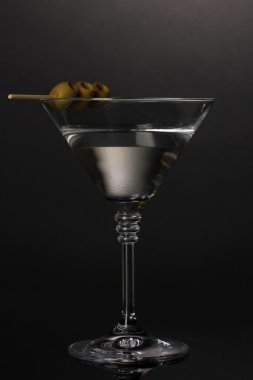 Martini kadehi ve gri arka plan üzerine zeytin