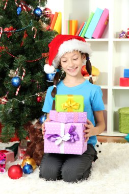 Hediyelik kutu Noel ağacının yakınında tutan küçük bir kız