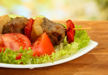 Lezzetli ızgara et ve sebzeler tabakta, ahşap masada.