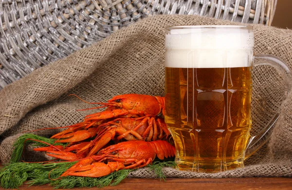 Tasty boiled crayfishes and beer on table on sackcloth background — Stock Photo, Image