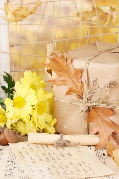 Jesienny skład z prezentu, kwiatów i liści na jasnym tle — Zdjęcie stockowe