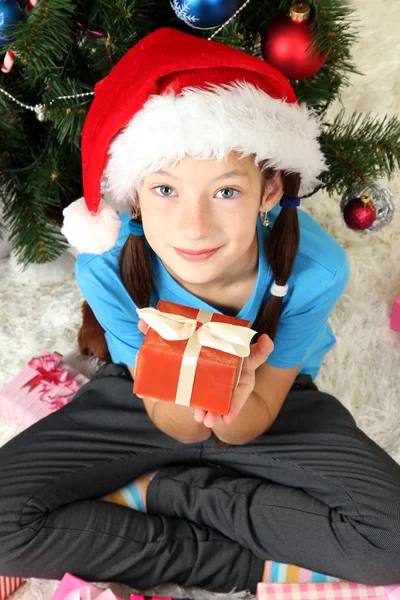 Menina segurando caixa de presente perto da árvore de Natal — Fotografia de Stock