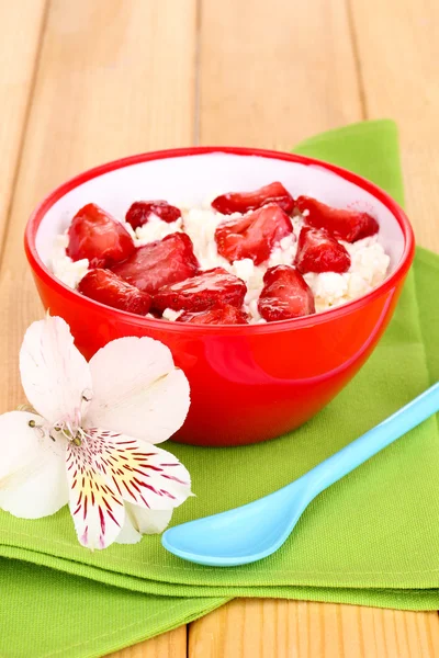 Τυρί cottage σε κόκκινο μπολ με φέτες τις φράουλες στο ξύλινο τραπέζι — Φωτογραφία Αρχείου