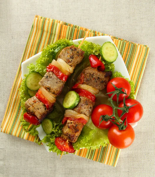 Вкусное мясо на гриле и овощи на шампуре на тарелке, на столе — стоковое фото