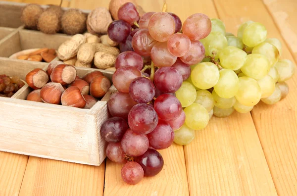 Grape with nuts on wooden table — Stockfoto