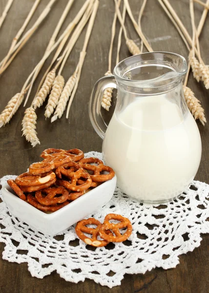 Gustosi pretzel in ciotola bianca e brocca di latte sul tavolo di legno primo piano — Foto Stock