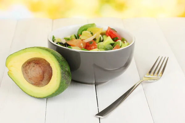 Вкусный салат авокадо в миске на деревянном столе на естественном фоне — стоковое фото