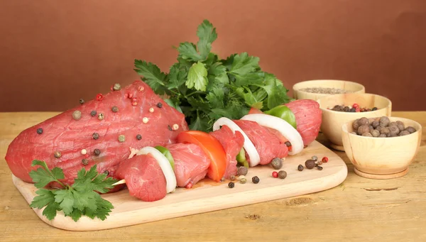 Raw beef meat marinated with herbs and spices on wooden table on brown background — Stock Photo, Image