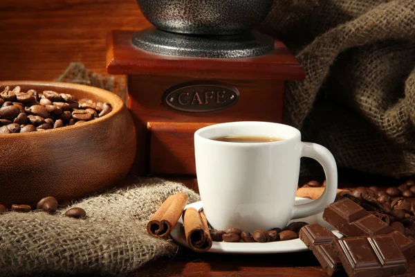 Coffee grinder and cup of coffee on brown wooden background — Stock Photo, Image