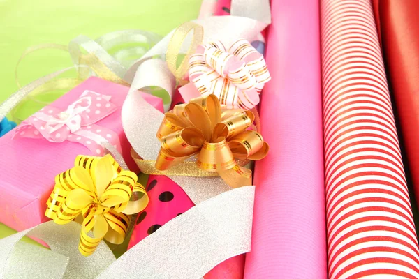 Rolls of Christmas wrapping paper with ribbons, bows on color background — Stock Photo, Image