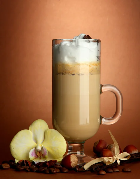 Caffè al latte profumato in tazza di vetro con spezie, su fondo marrone — Foto Stock