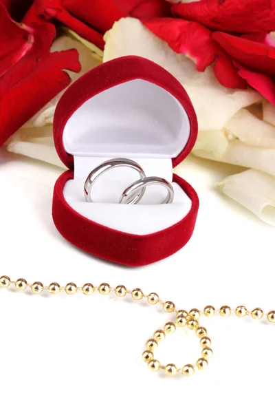 Krásná krabice se snubními prsteny na červených, bílých a růžových okvětních lístků růží pozadí izolované na bílém — Stock fotografie