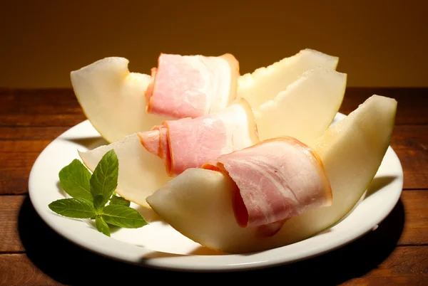 Jamón y melón parma, sobre mesa de madera, sobre fondo amarillo —  Fotos de Stock